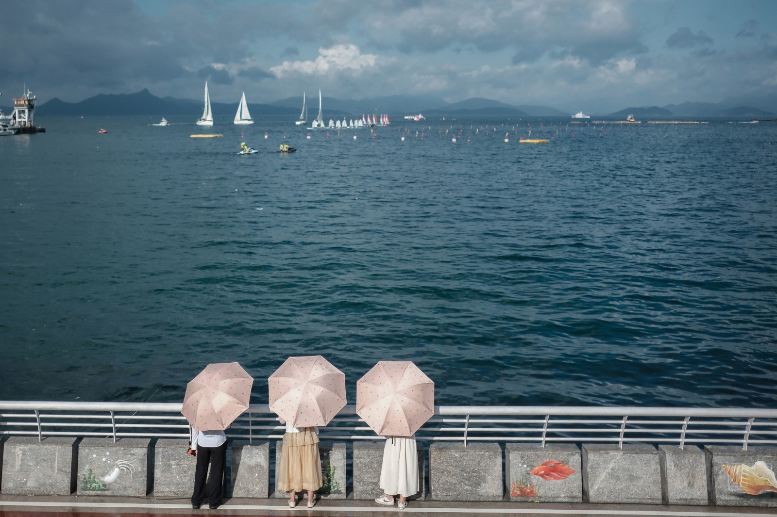 看 海-2023年6月20日，深圳南澳海邊，烈日下，游客打傘看海，遠(yuǎn)處是在為端午舉辦龍舟賽正在進(jìn)行訓(xùn)練的賽手們。-薛云麾.jpg